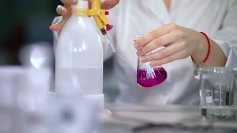 Scientist-hands-working-with-liquid-in-medical-lab.-Glassware-in-doctor-hands